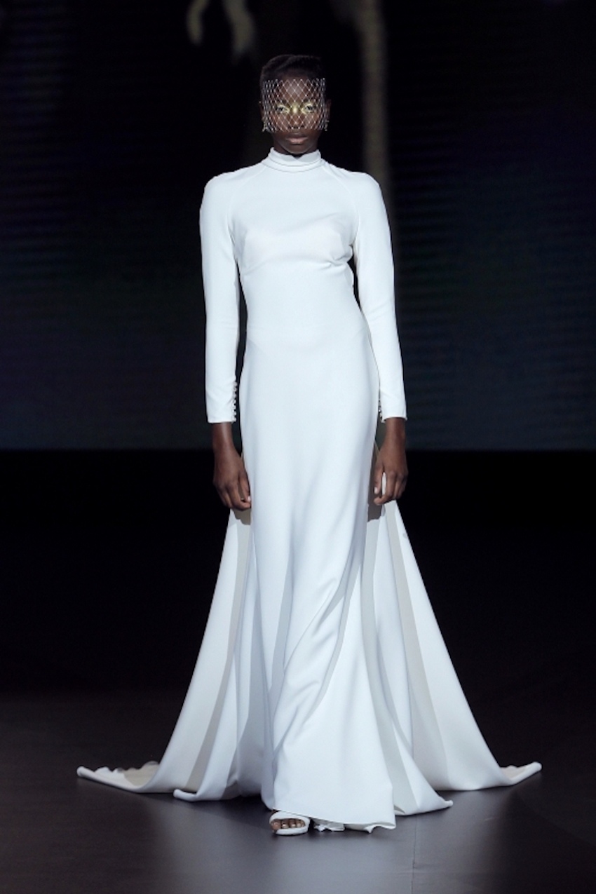 A Yolancris bridal model wearing a full length, long-sleeved minimalist dress