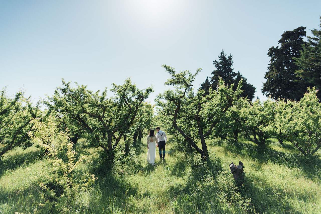 A bride and groom walking away in the countryside while holding hands
