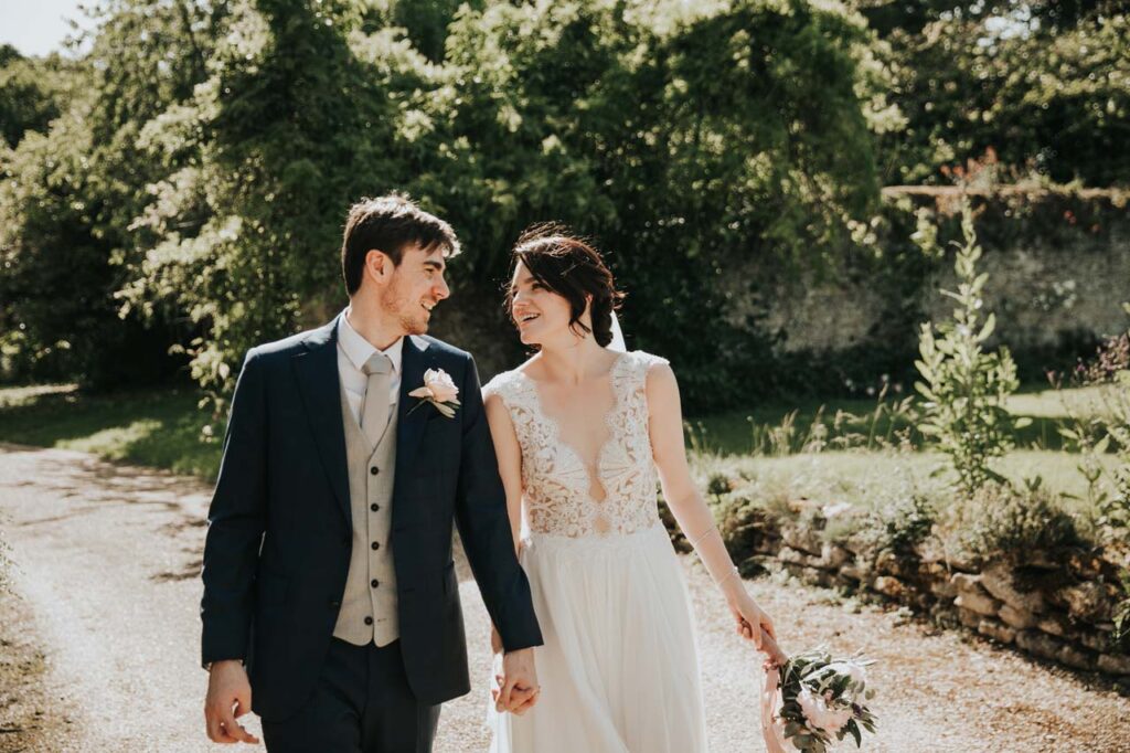 A couple holding hands walking down a path at their formal destination wedding